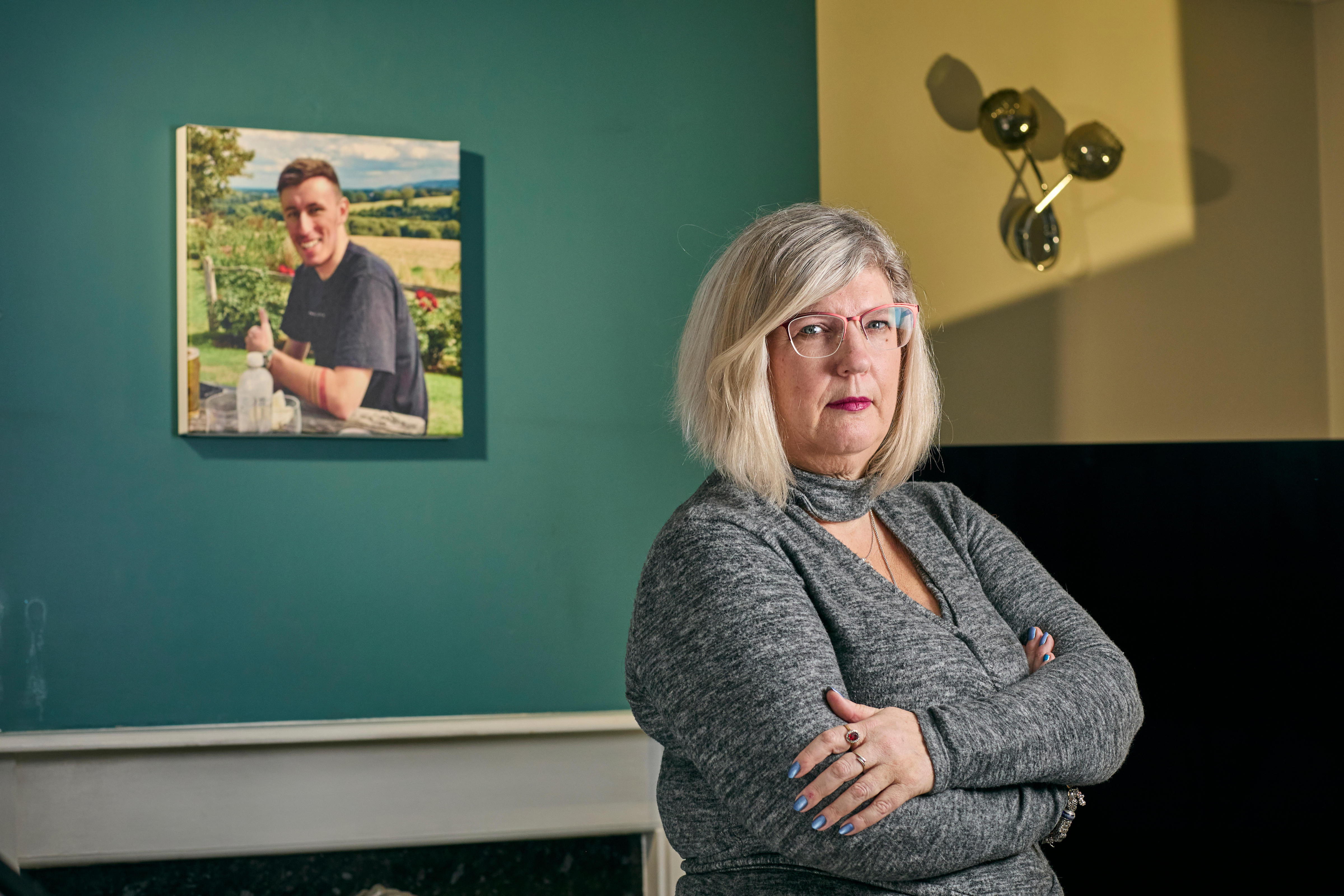 Caroline wearing a grey dress stands in front of a painting of Bradley