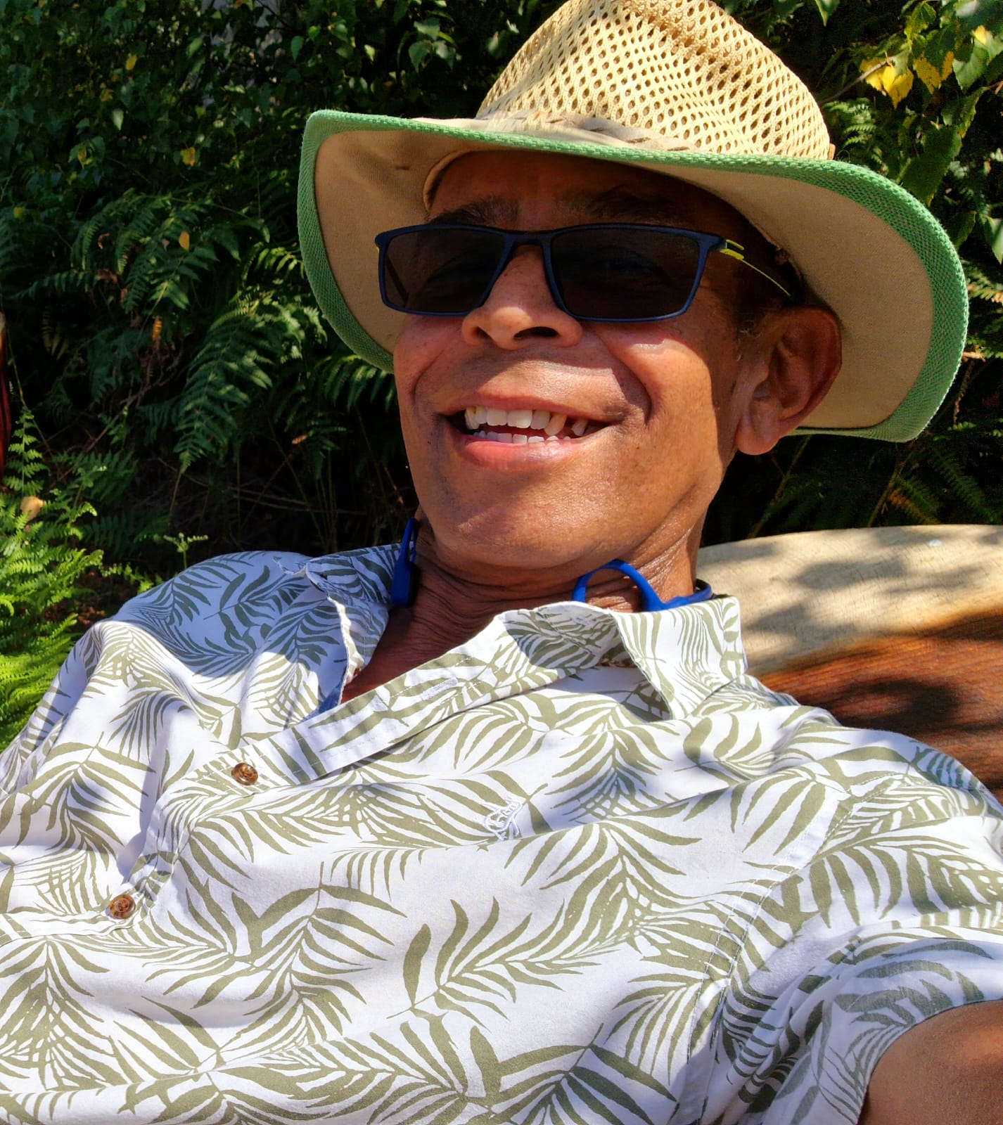 Chris wearing a hat and sunglasses smiles for the camera