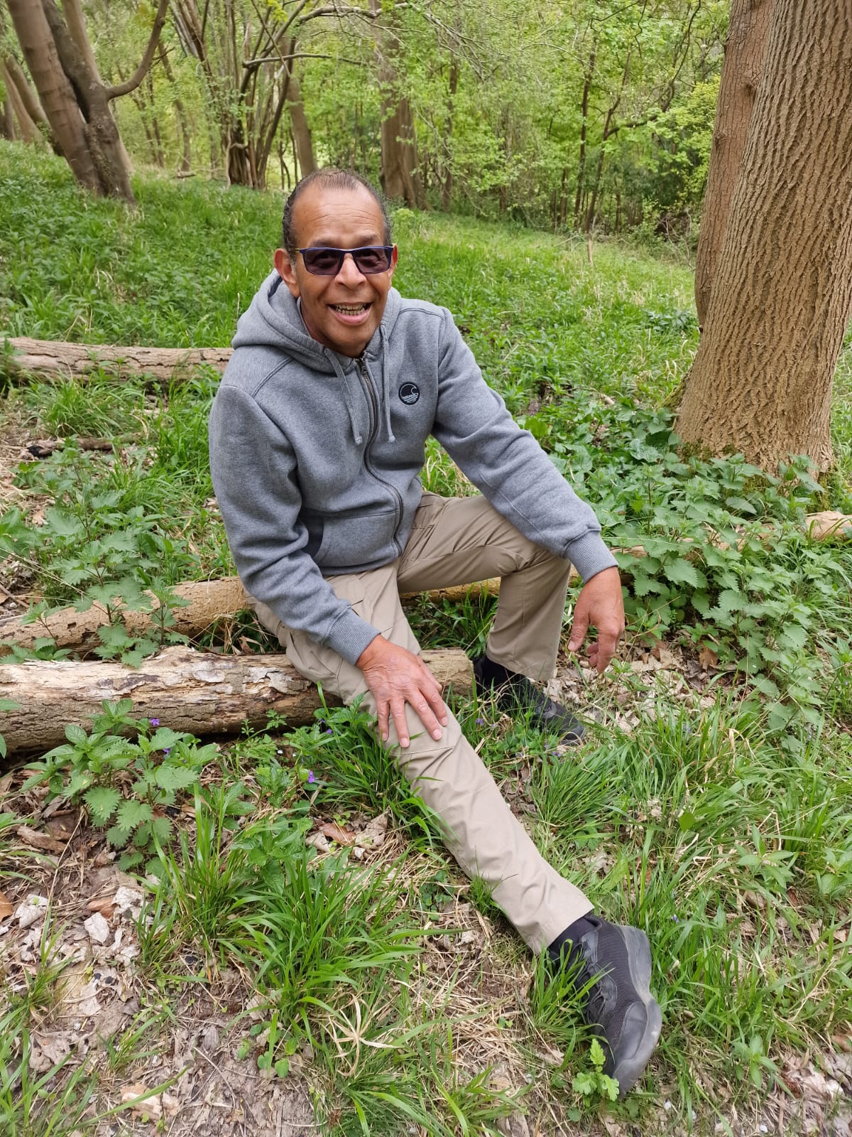 Chris sits in a relaxed pose in woodland