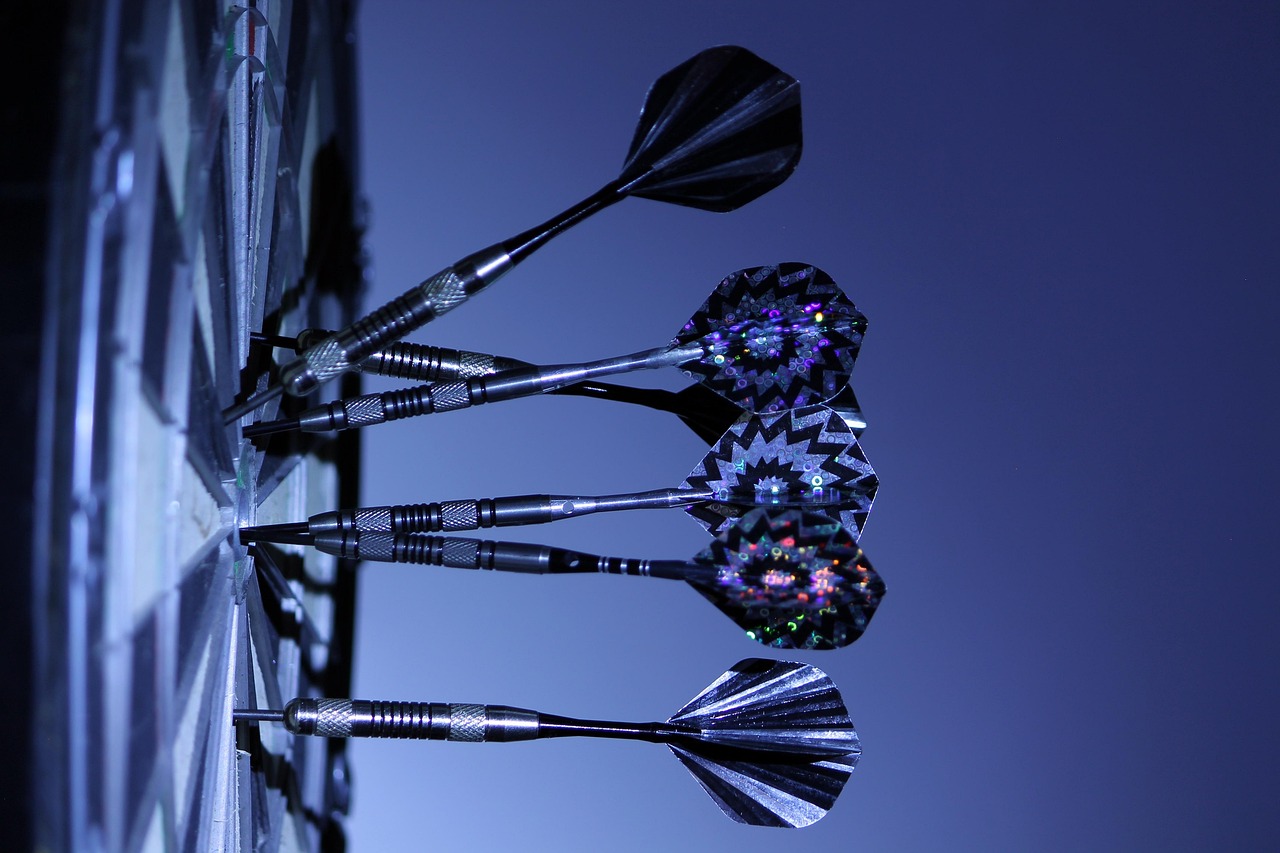 Side view of six darts pinned on a dartboard