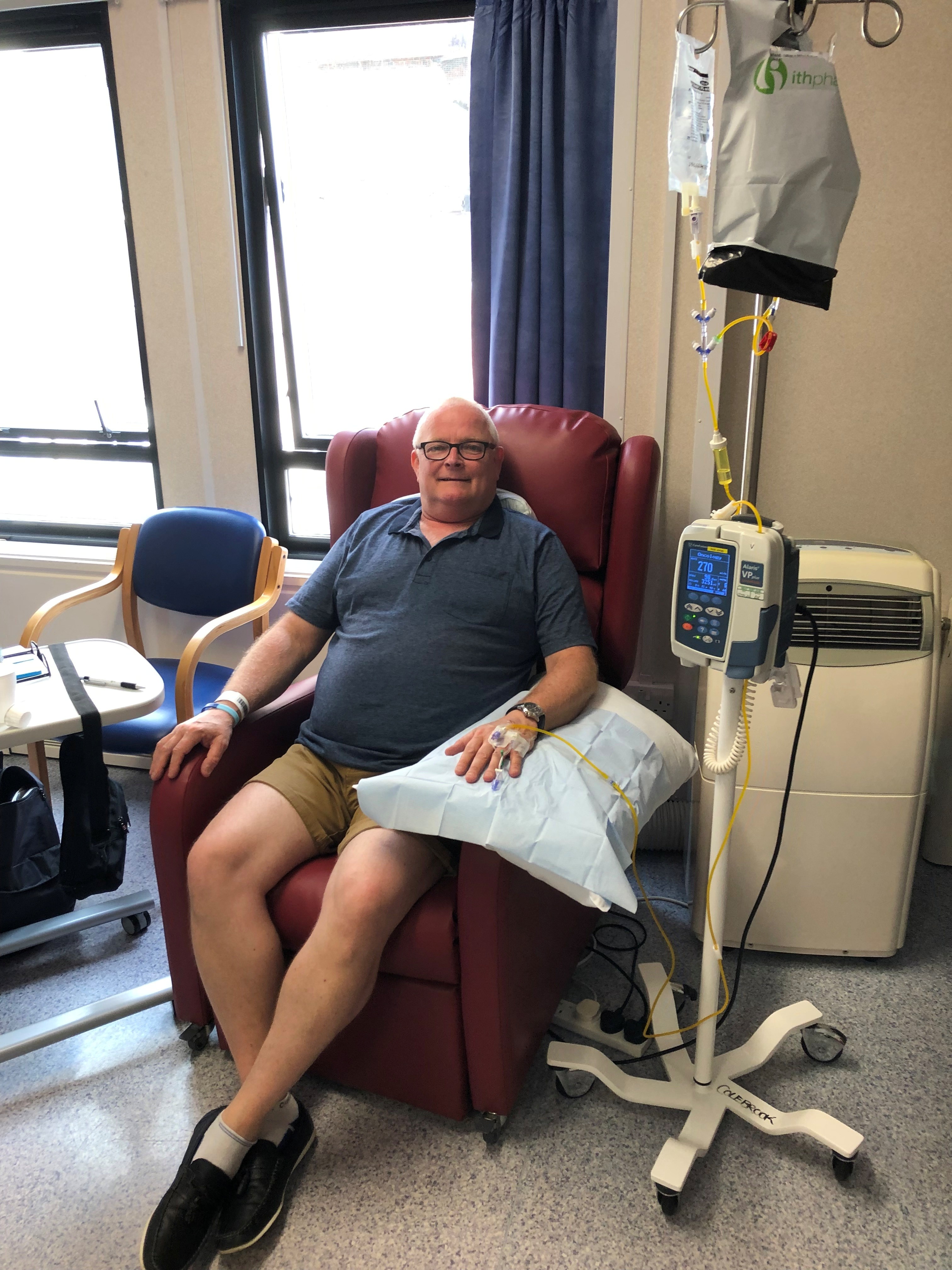 Dave is sitting in a treatment chair attached to a drip