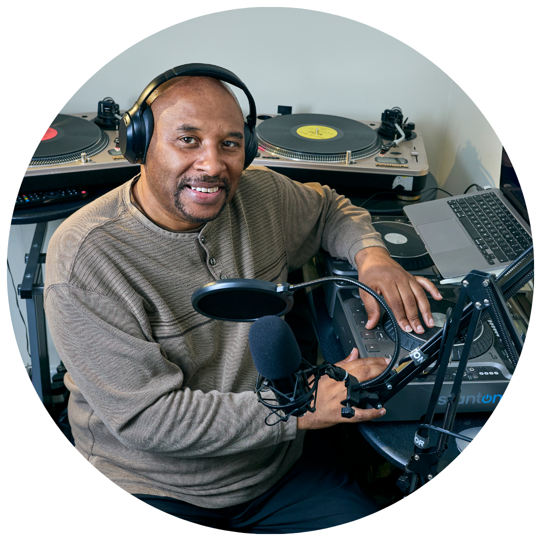 Godfrey Fletcher, smiling next to his DJ equipment.