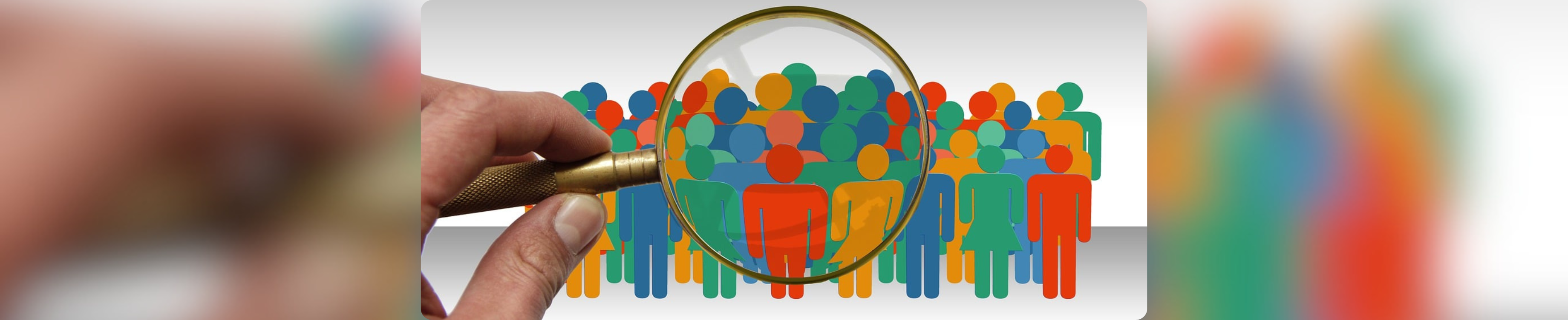 Hand holding magnifying lens pointing at group of different coloured illustrated figures