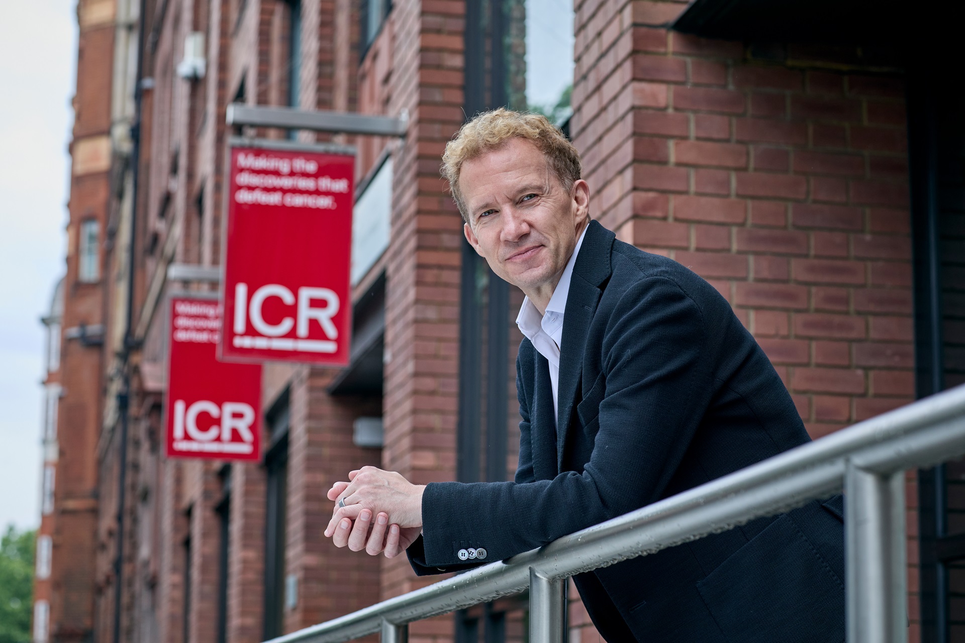 Image of scientist Chris Bakal leaning on a rail outside the Chester Beatty Laboratories