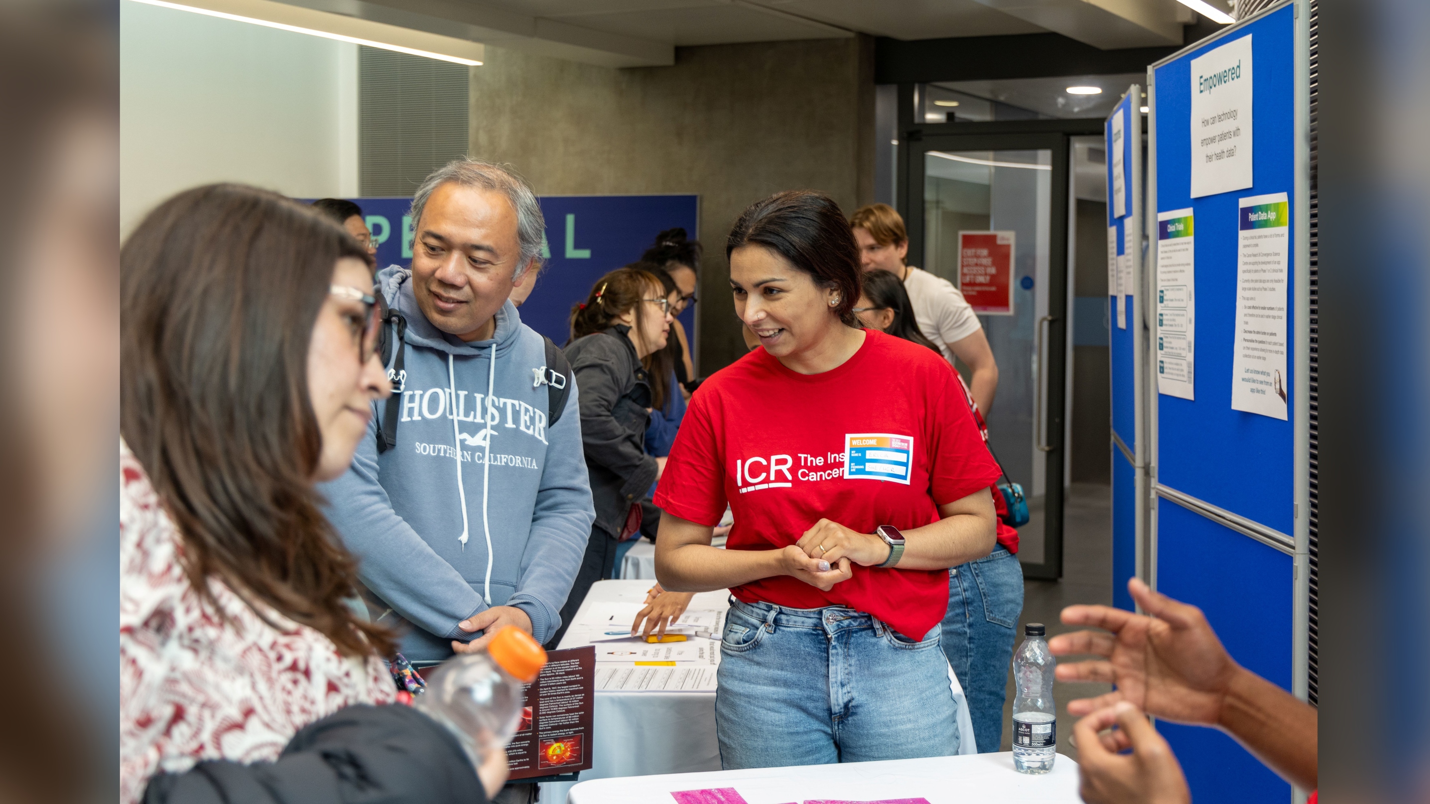 Erica Oliveira smiling, listening to someone at a public engagement event