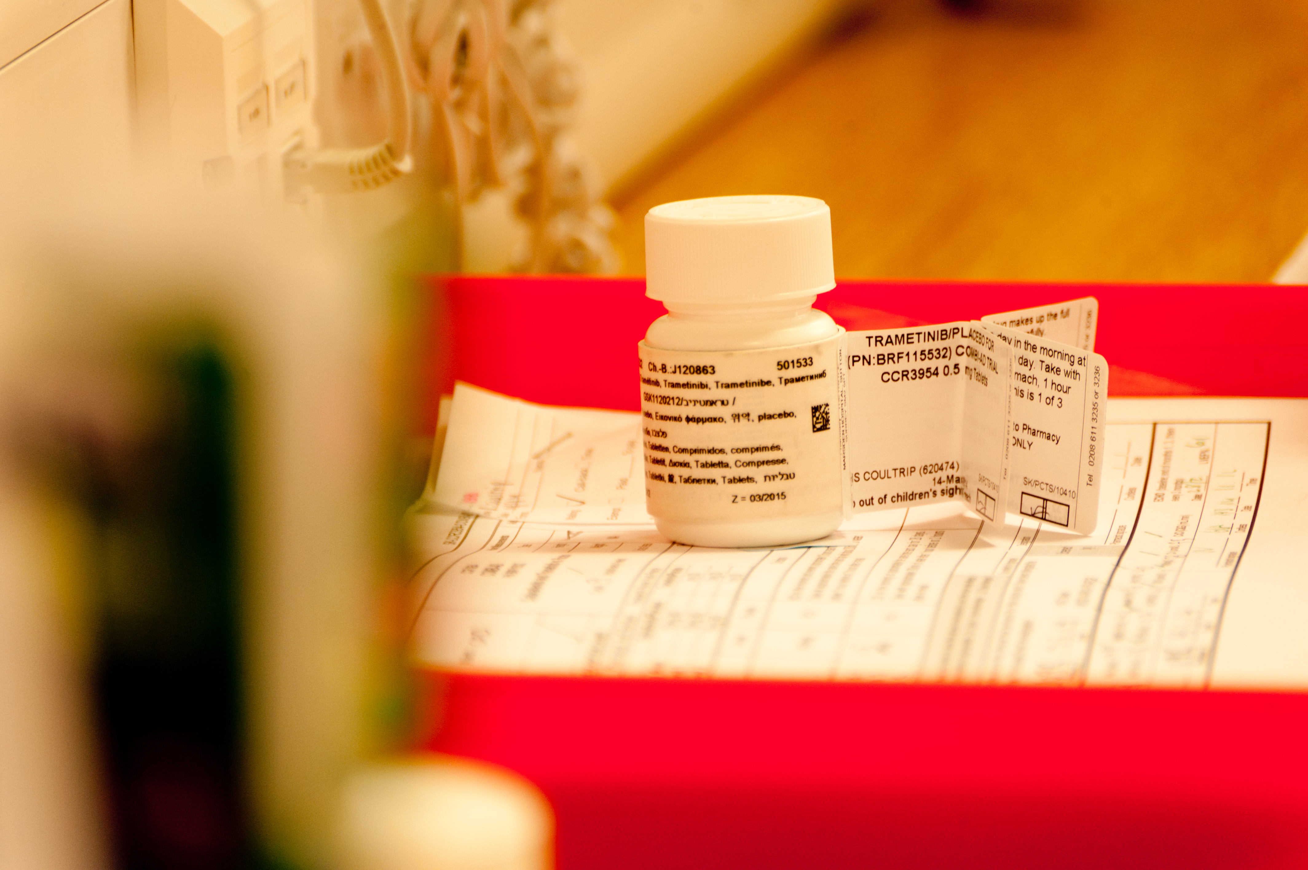 A pill bottle with label sat on top of a filled out form for a clinical trial