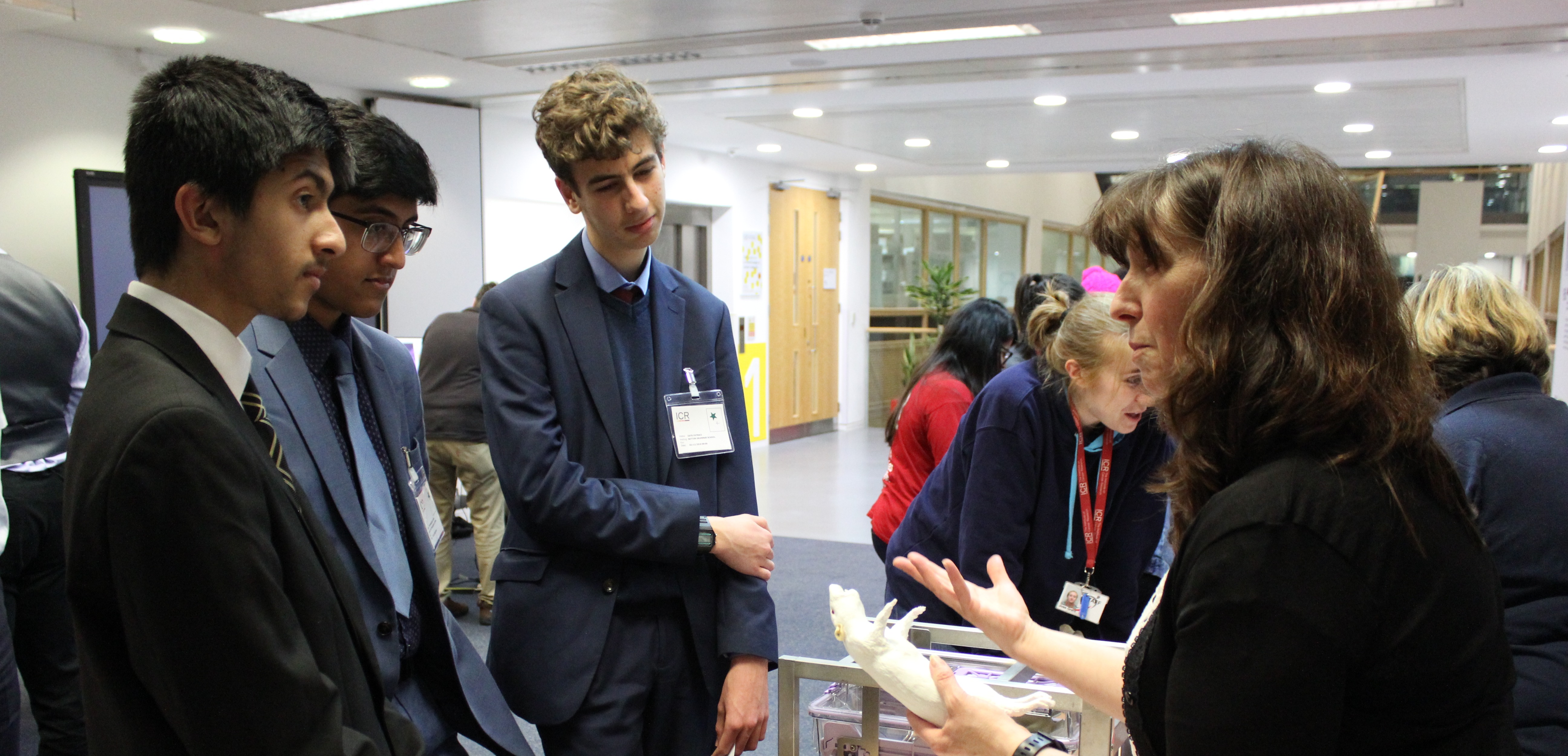 Researcher explaining something to three students at a public engagement event