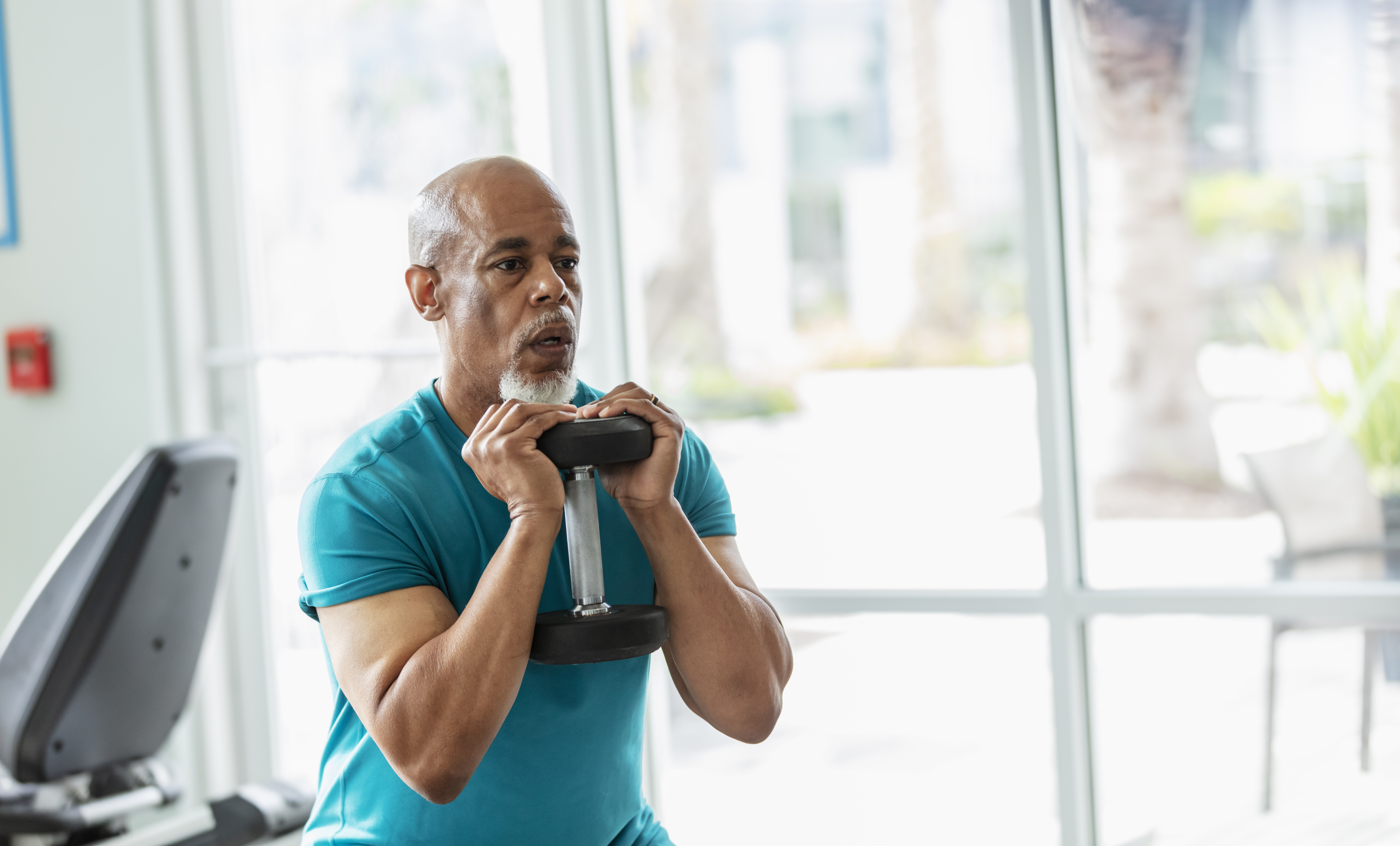 Senior man lifting weights at the gym
