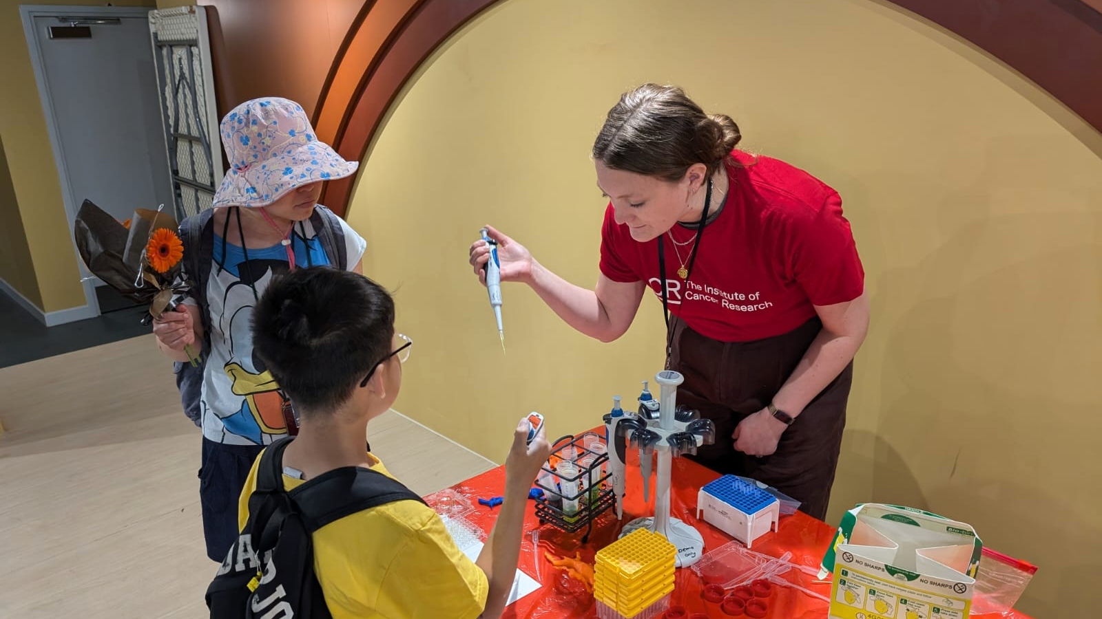 ICR public engagement volunteer showing two children how to use a pipette